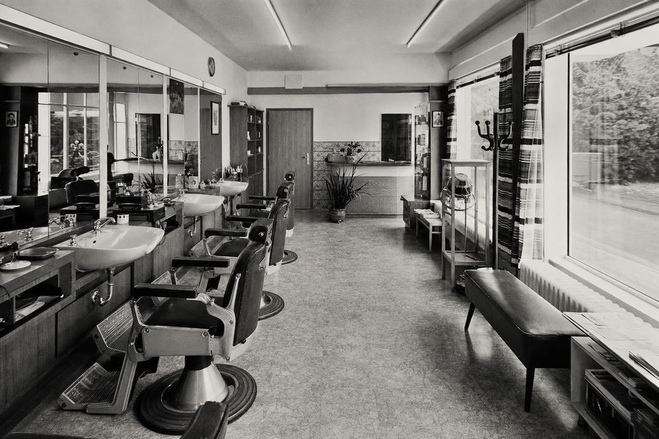 Schwarz-weißes Stimmungsbild: Fassade eines traditionellen Herrenfriseursalons bei Tageslicht, ruhig und sachlich